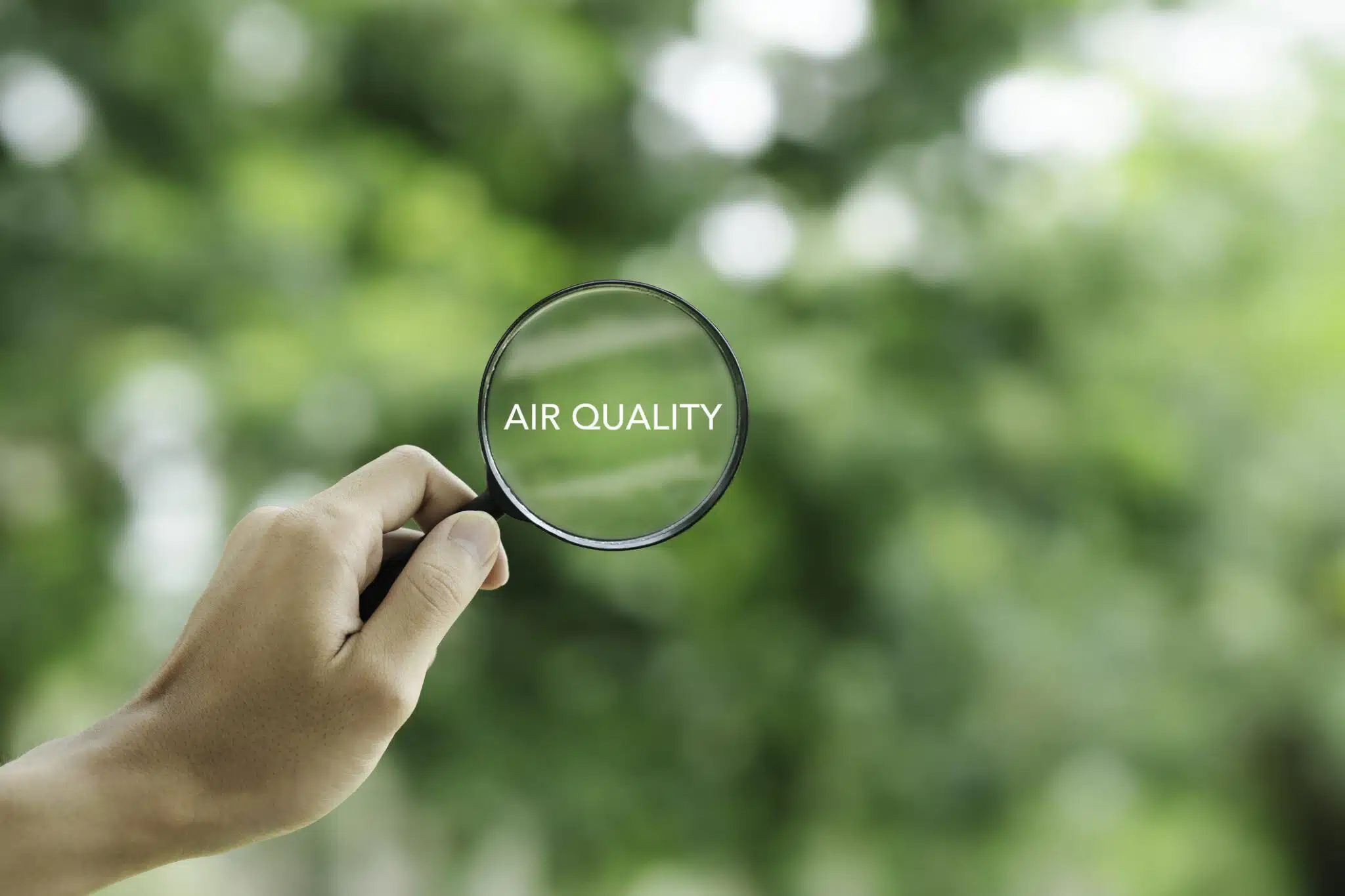 hand holding a magnifying glass to check the good air quality and clean outdoor air quality safe from pollution dust PM 2.5, Indoor Air Quality.