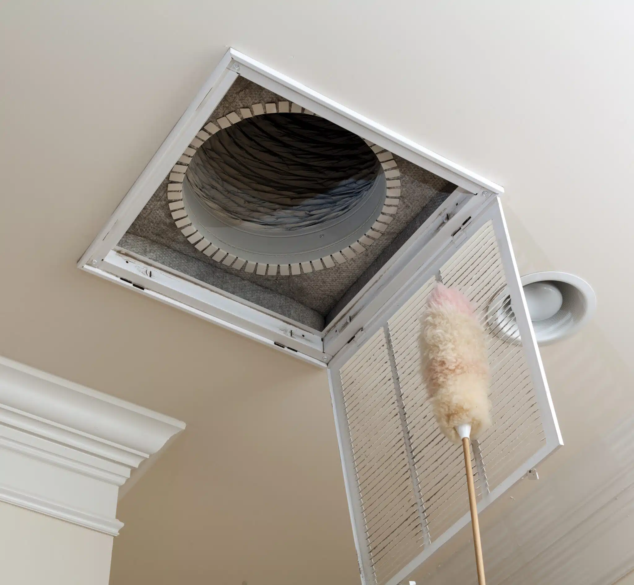 Dusting the Air Conditioning Vent Filter in the Ceiling of a Modern Home for Better Ventilation.