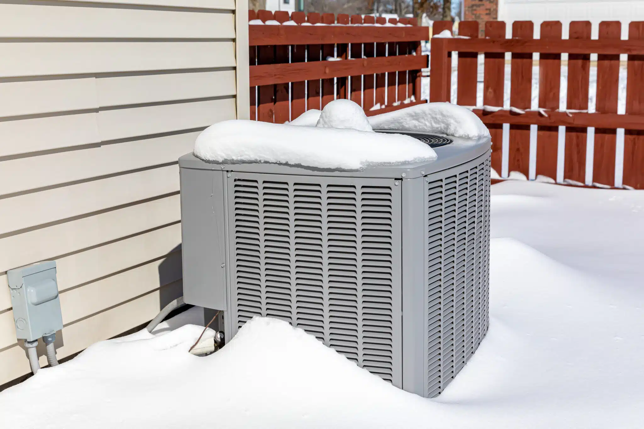 House air conditioning unit covered in snow during winter, Emergency Heat Mode.