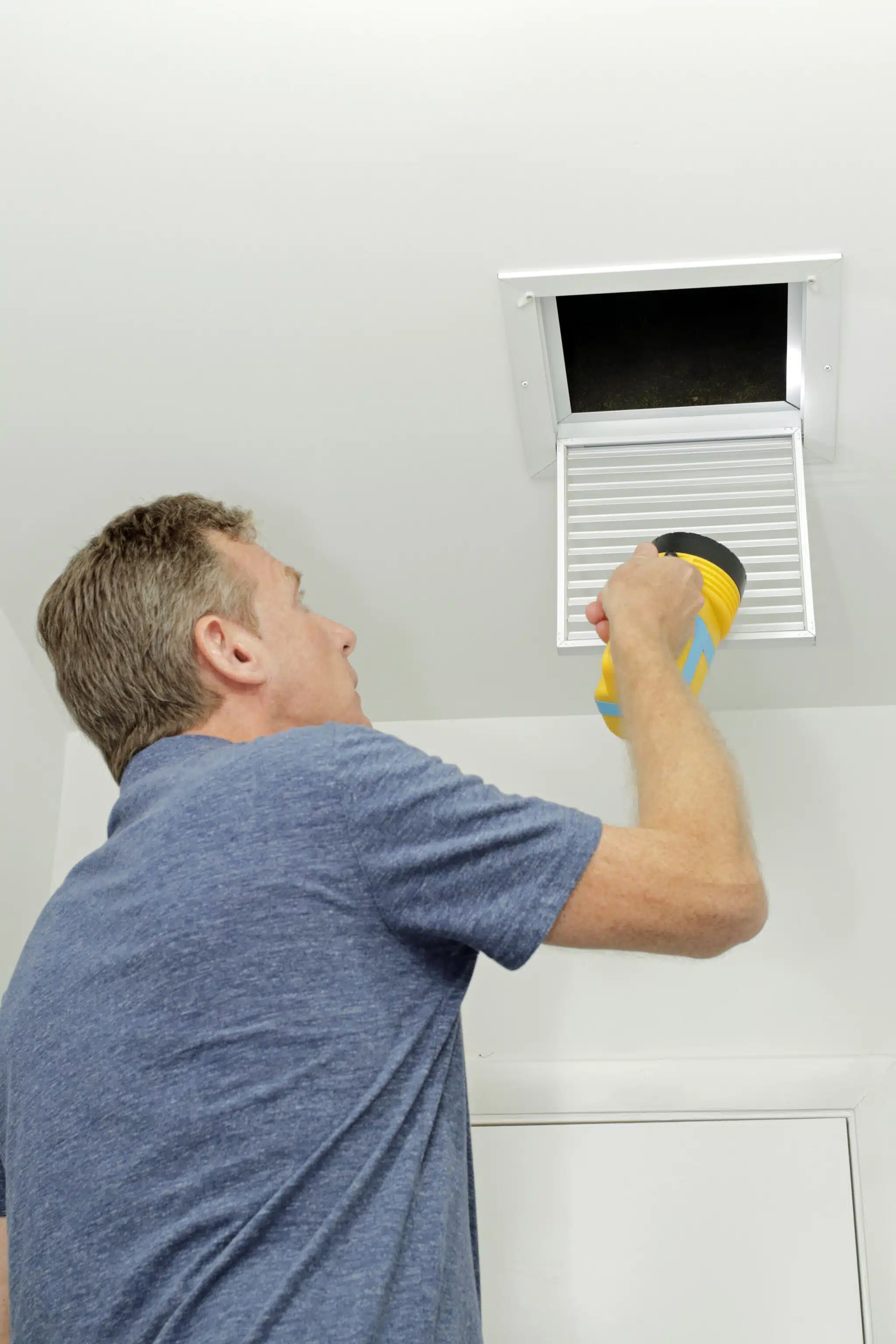 Male examining the cleanliness of a small home HVAC air duct, Air-Exchange Systems.