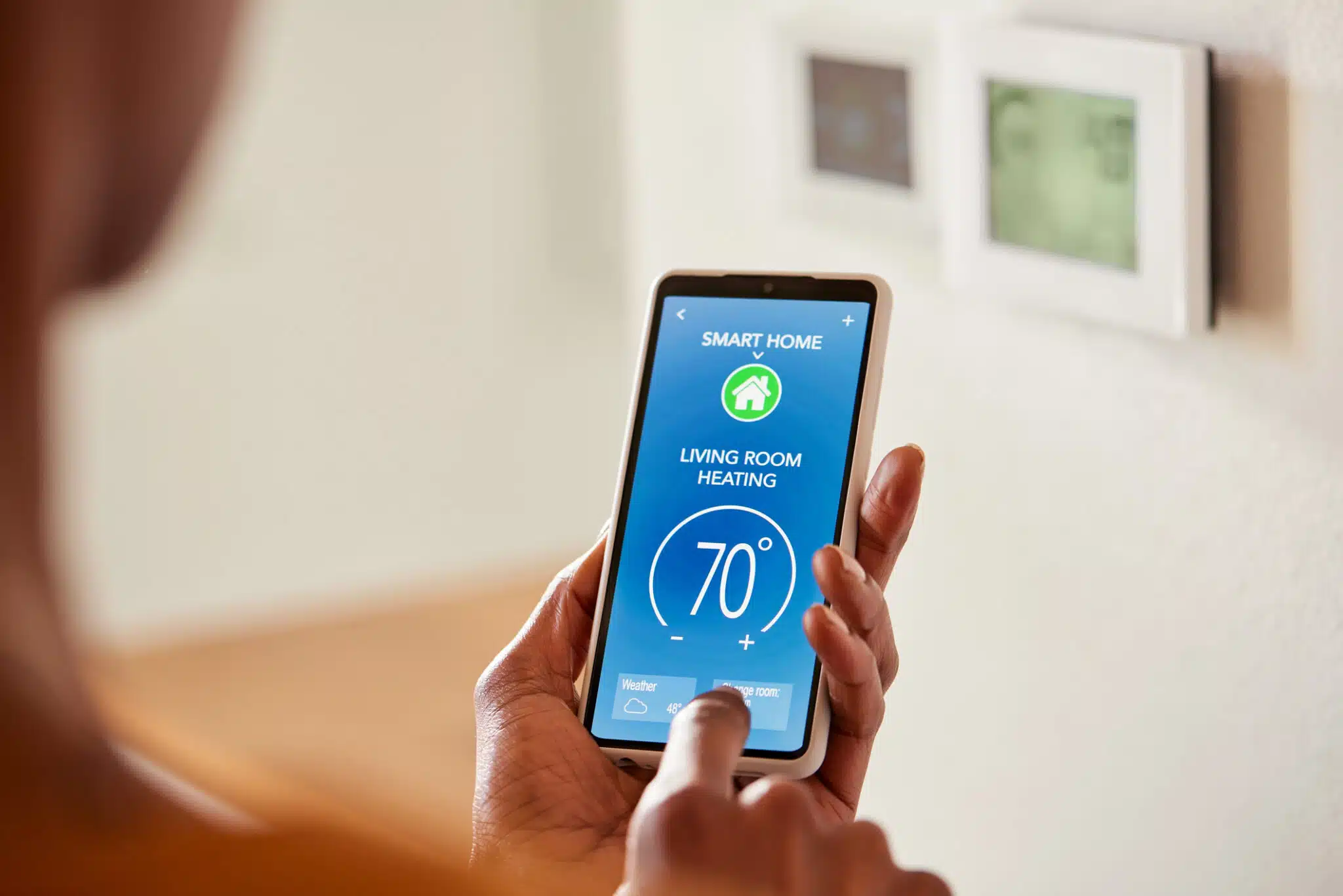 Woman adjusting home temperature on mobile phone, Programmable Thermostat.