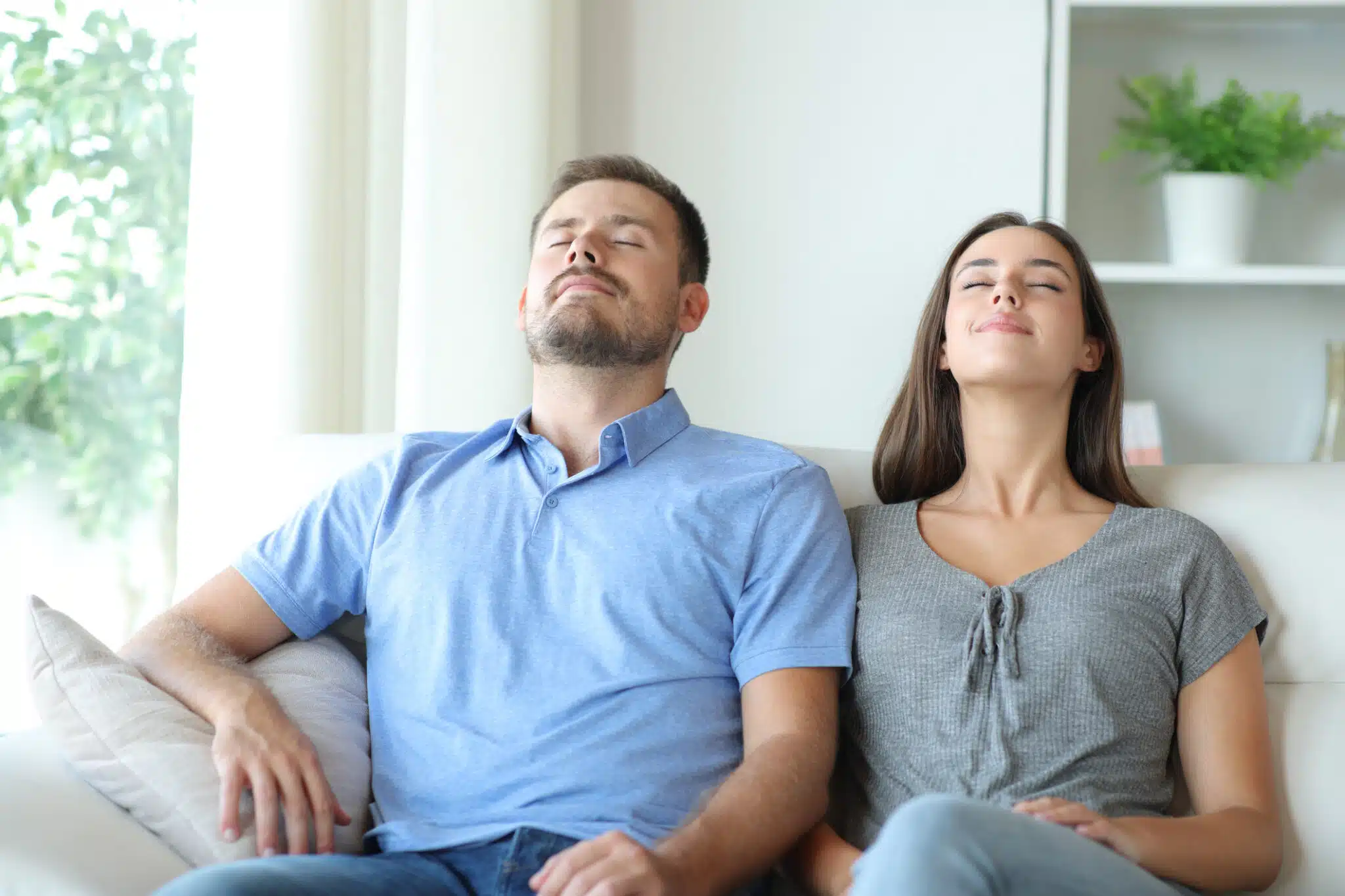 Couple relaxing at home breathing fresh air on a sofa, High-Efficiency HVAC Filters.