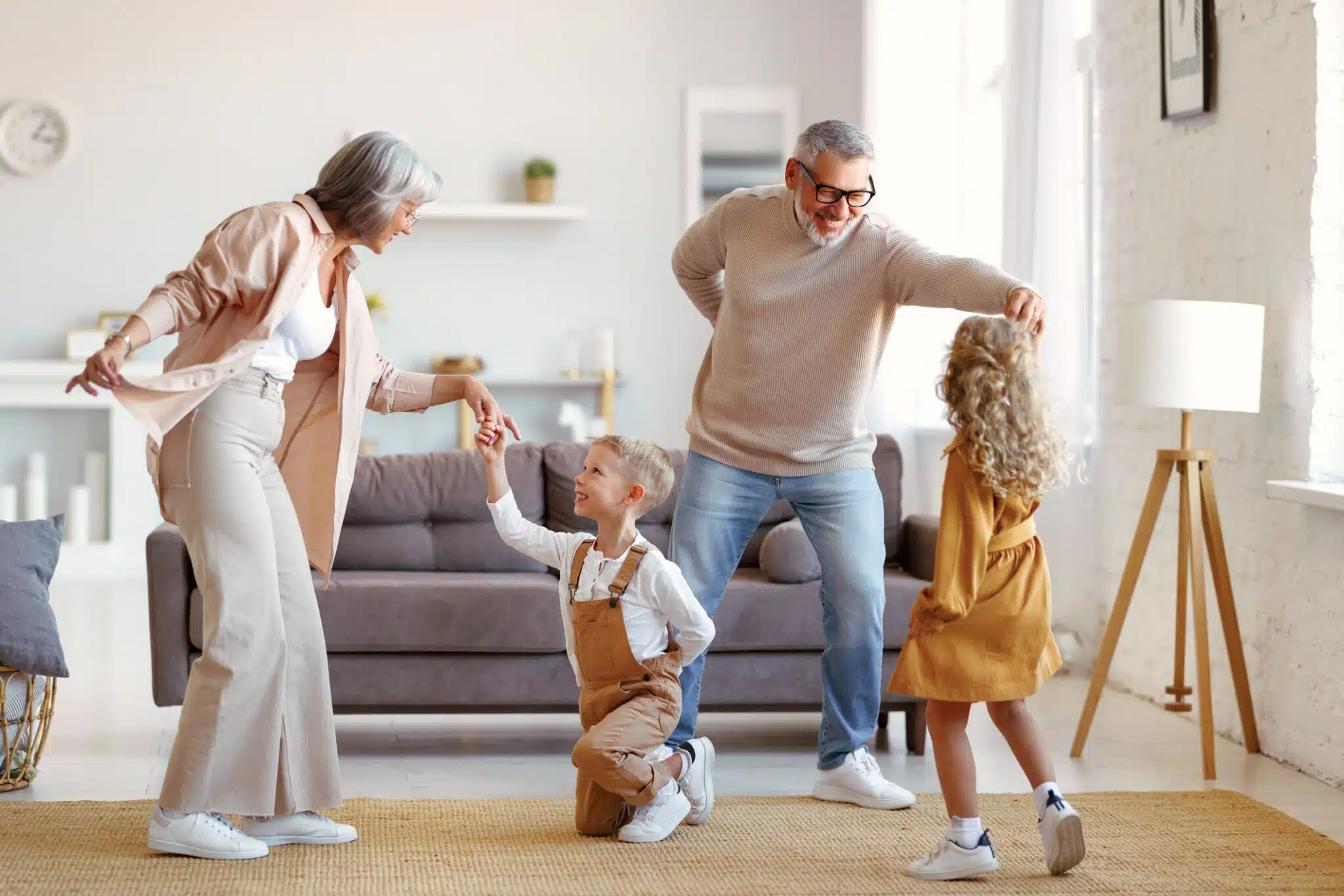 Active senior grandparents dancing with two happy kids grandchildren in living room, HVAC Airflow.