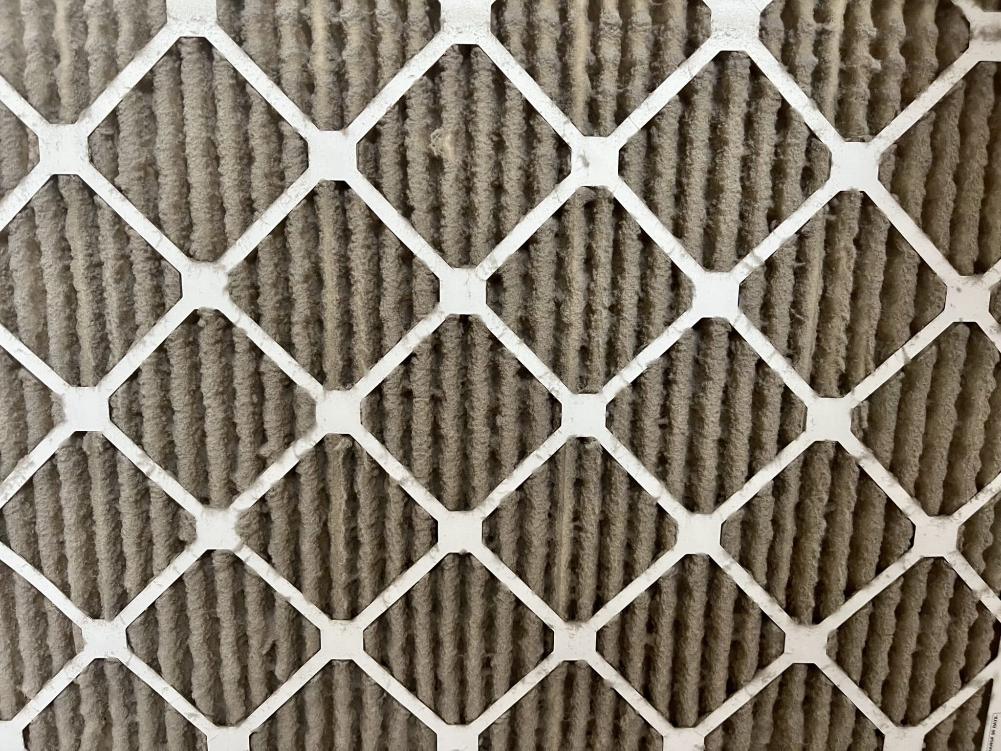 A man holding a dirty filter that was removed from the air conditioner, Annual HVAC System Evaluations.