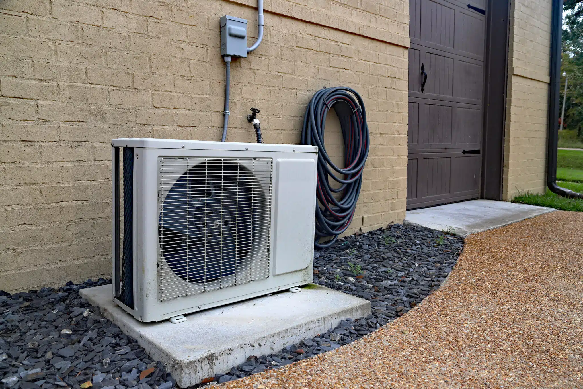 Air Conditioner ductless mini split system next to home with brick wall, Seamless HVAC Integration.