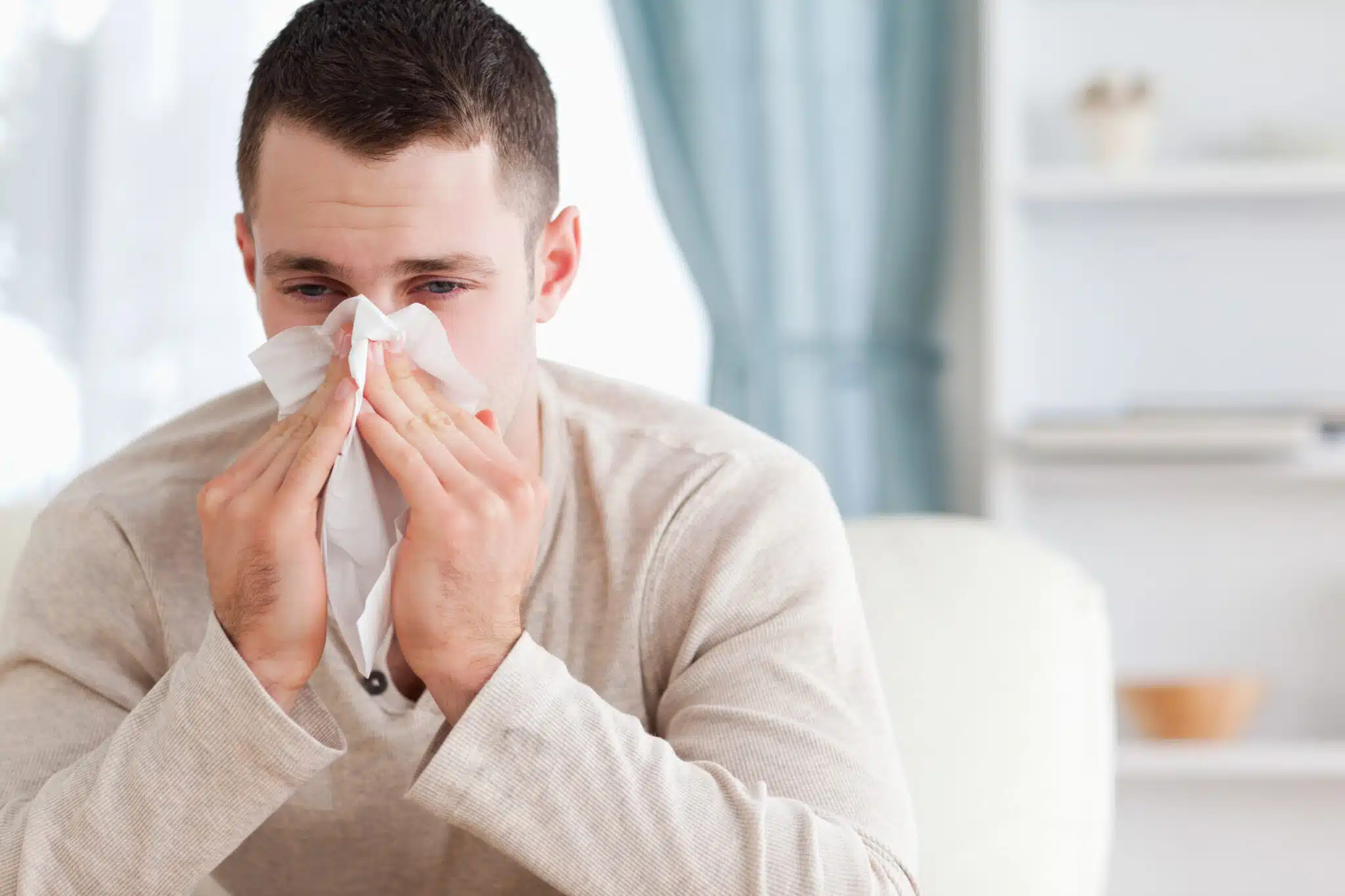 Man blowing his nose because of an allergy, HVAC Coil Cleaning.
